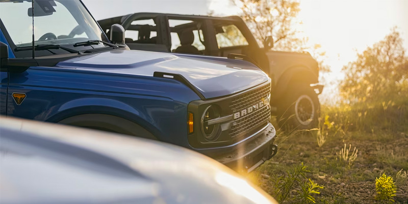 All new Ford Bronco's lined up on a hill overlooking the sunset. - Franklin Ford Franklin, MA